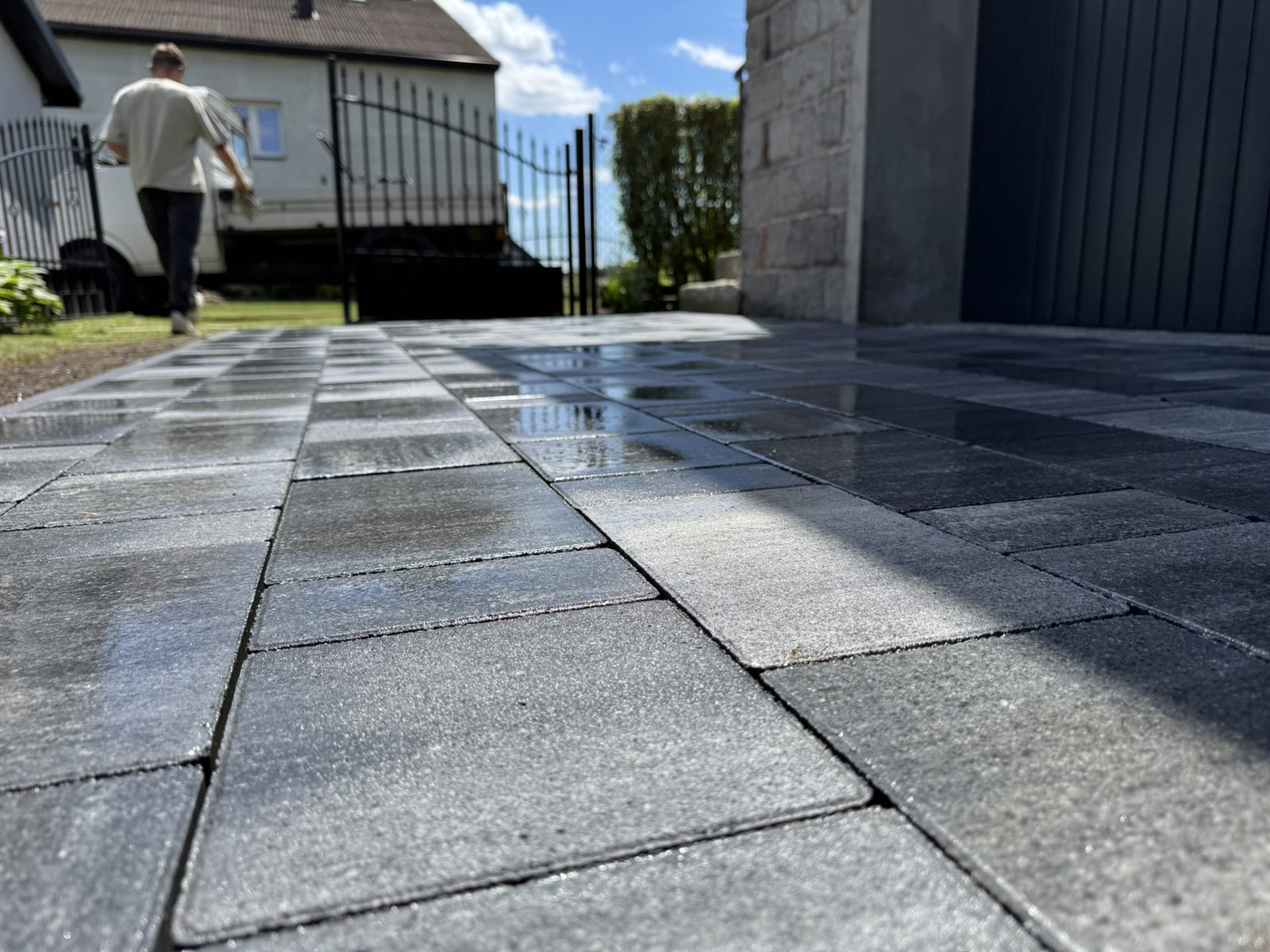 Podjazd z szarej kostki betonowej prowadzący od bramy do garażu